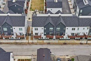 A row of modern townhouses with a central courtyard, visible balconies, and a paved street.