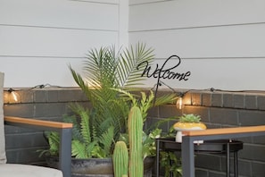 A corner with a 'Welcome' sign, potted plants, and a small table with a chair.