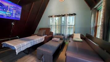 A loft-style room with a television, a sofa, a bench, and a bed.