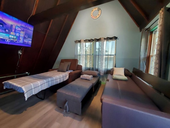 Una habitación estilo loft con televisión, sofá, banca y cama.