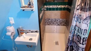Un bagno con doccia, lavandino, specchio e porta asciugamani.