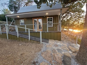 A small building with a porch, a staircase, and a stone pathway.