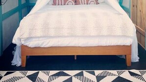 A bed with a canopy, a window, and a patterned rug.