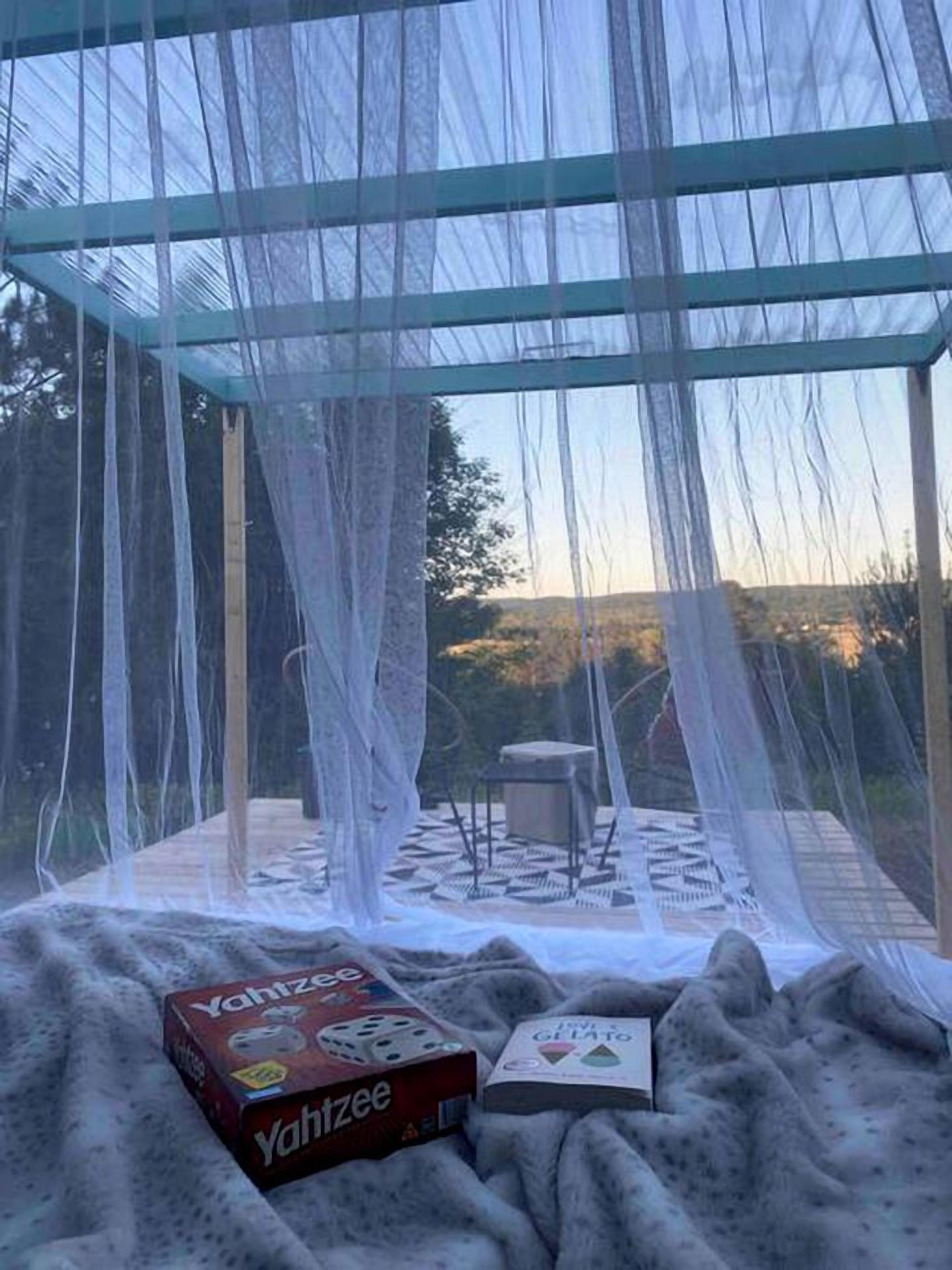 A room with a glass ceiling, a blanket, a board game, and a book.