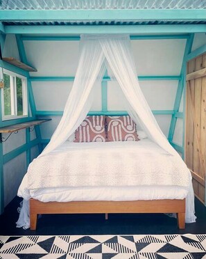 A bed with a canopy, a window, and a patterned rug. - A-Frame Serenity: Tiny Cabin with Panoramic Scenery in Michigan's Tranquil Setting (Boyne Falls)