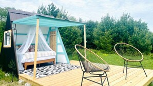 Una carpa con una cama y dos sillas en una terraza de madera.