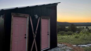Una pequeña estructura de madera oscura con dos puertas rosas y un farol en la pared.