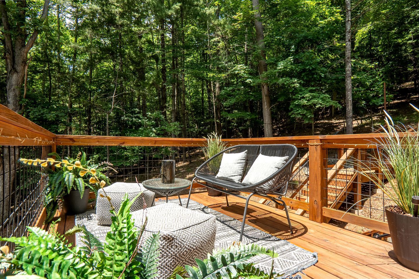 Una terraza de madera con mobiliario exterior, rodeada por un bosque.