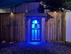 Ein Holzzaun mit einer Tür, beleuchtet von blauem Licht.