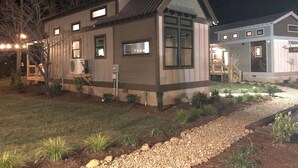 Een huis met twee verdiepingen, een schuin dak, een voortuin en een verzorgde tuin.
