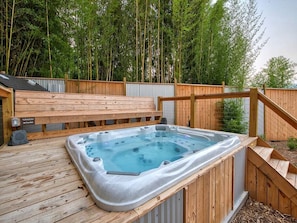 A hot tub on a wooden deck with a wooden fence and bamboo in the background. - Luminous Modern Tiny House Perfect for Couples in North Carolina (Waynesville)