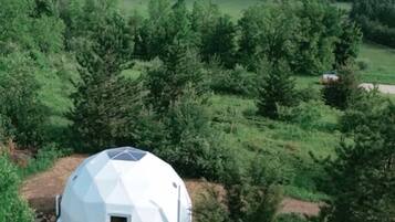 Eine geodätische Kuppel inmitten eines bewaldeten Geländes mit freiem Blick auf die umliegende Landschaft.