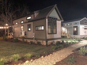 Una casa de dos pisos con techo inclinado, un porche delantero y un jardín bien cuidado.