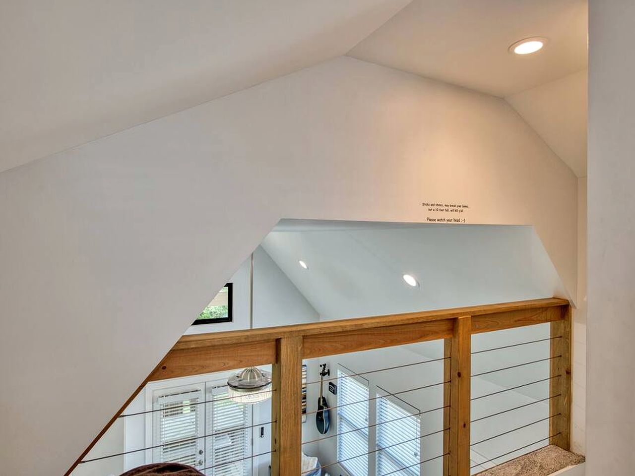 A modern interior with a wooden staircase, white walls, and a ceiling with recessed lighting.