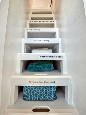 Een trap met tekst die een humoristische boodschap geeft over het uittrekken van schoenen voor het beklimmen.