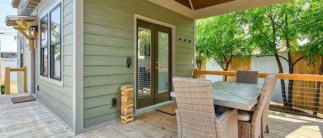 A covered patio with a table and chairs, a door, and a window.