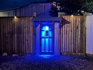 Una cerca de madera con una puerta iluminada por luz azul.