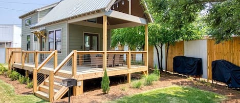A single-story house with a porch, a covered deck, and a fenced backyard.