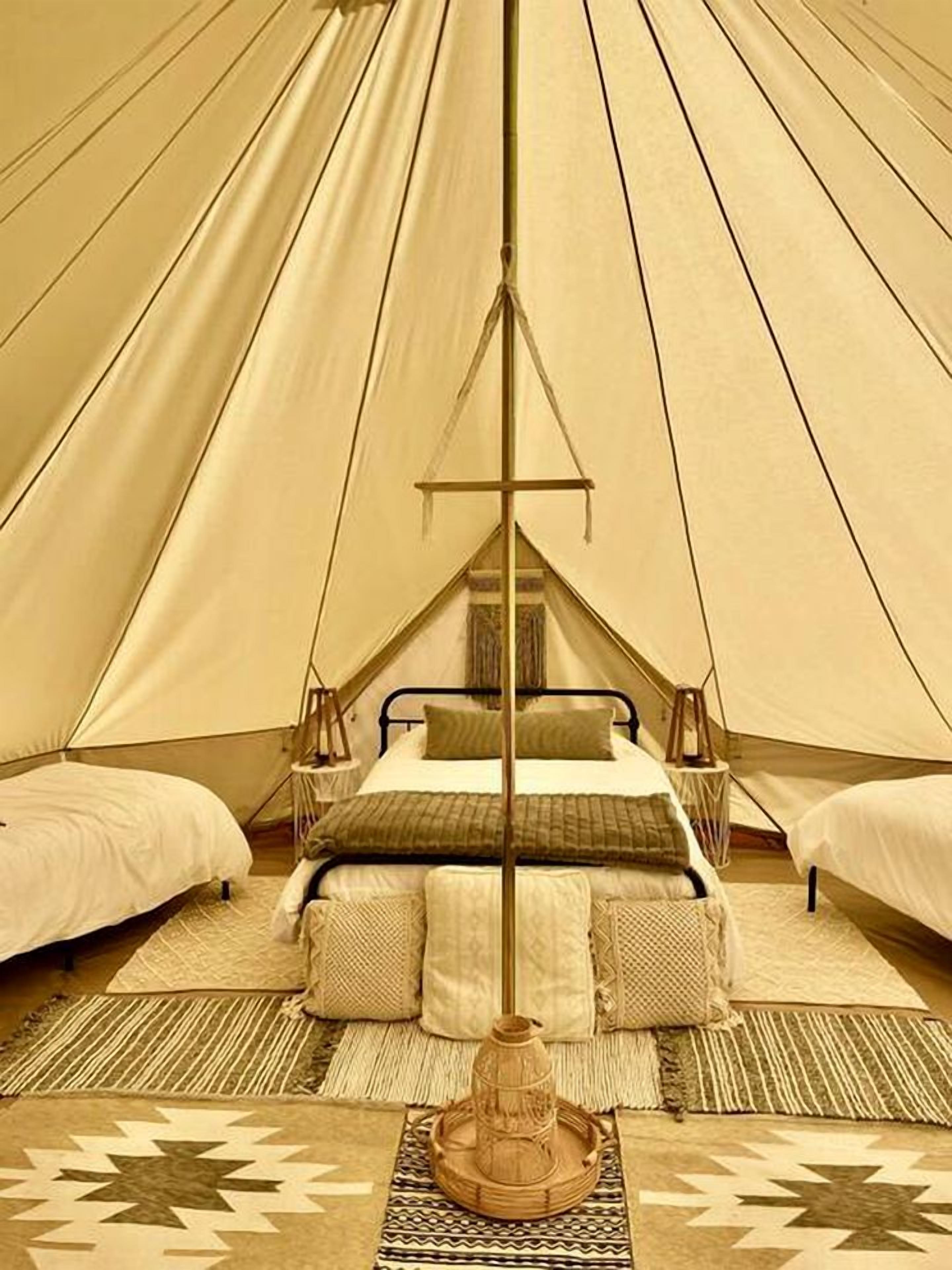 A tent with a central bed, two smaller beds, and a central pole.