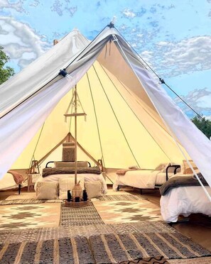 A large tent with a central pole, two beds, and a hanging lantern.