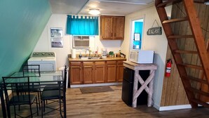 A kitchen with wooden cabinets, a stove, and a dining area with chairs.