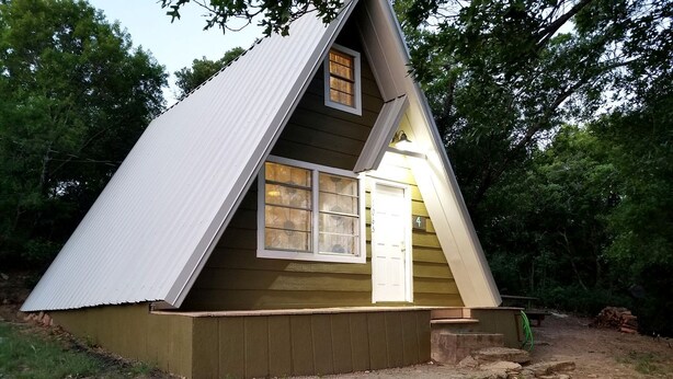 A small, single-story wooden cabin with a gabled roof, a front door, and a window.