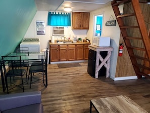 Una cocina con armarios de madera, una estufa y un comedor con sillas.