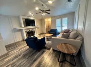 A modern living room with a ceiling fan, a fireplace, a sofa, and a coffee table. - *Extended Stay: Backyard, Garage, Fireplace* (Carrollton)