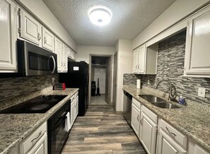 A kitchen with granite countertops, stainless steel appliances, and a tiled backsplash. - *Extended Stay: Backyard, Garage, Fireplace* (Carrollton)