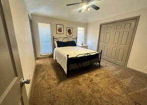 A bedroom with a bed, a ceiling fan, and a door. - *Extended Stay: Backyard, Garage, Fireplace* (Carrollton)