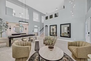 A spacious living area with a round coffee table, two armchairs, a dining area with a dark wood table and chairs, and a large mirror above the dining table. - Stylish Family Getaway | Fully Furnished Home (Las Vegas)