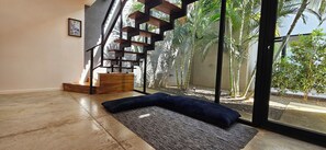 Ein Zimmer mit großem Fenster, einer Holztreppe und Blick auf Palmen.