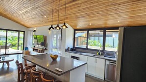 Una cucina moderna con soffitto in legno, isola centrale e un'ampia finestra.