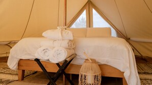 A tent with a bed, rolled towels, and a woven lantern. - Romantic Stargazing Retreat: Bell Tent for Couples in Michigan's Dream Destination (Boyne Falls)