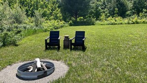 A grassy outdoor area with two chairs and a fire pit. - Romantic Stargazing Retreat: Bell Tent for Couples in Michigan's Dream Destination (Boyne Falls)