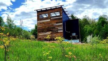 A modern wooden cabin with a sloped roof, large windows, and a small attached structure.