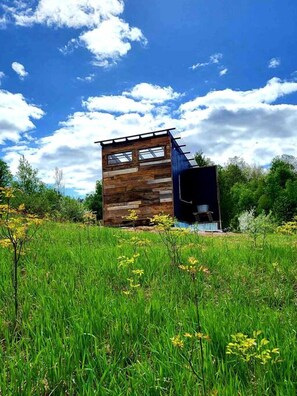 A modern wooden cabin with a sloped roof, large windows, and a small attached structure.