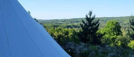 A large tent on a wooden deck with a clear view of a forested landscape.