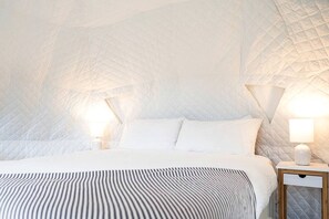 A bed with a quilted headboard, a bedside table with a lamp, and a patterned bedspread.