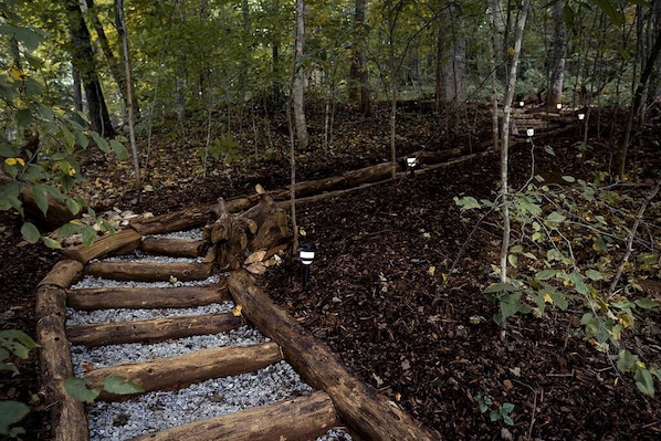 A wooden spiral staircase in a forested area with gravel steps.