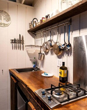 A kitchen with a wooden countertop, hanging pots, a gas stove, and a wine bottle.