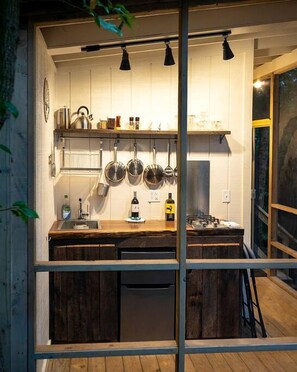 Una cocina pequeña con armarios de madera, un lavamanos y ollas colgadas.