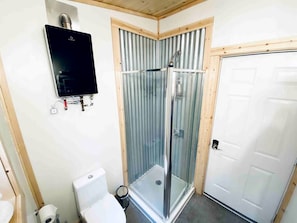 A small bathroom with a shower, toilet, and a white door.