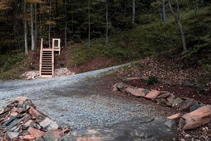 A forested area with a gravel path, a wooden gate, and a pile of rocks.