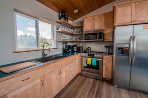 Une cuisine moderne avec des meubles en bois, un réfrigérateur en acier inoxydable, un four à micro-ondes et une cuisinière.