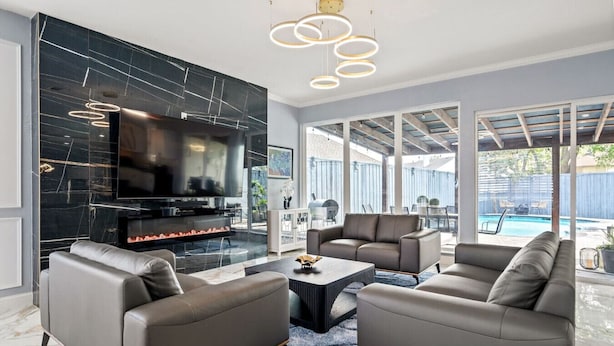 Una sala de estar moderna con chimenea, sofás de cuero, una mesa de centro y un televisor.