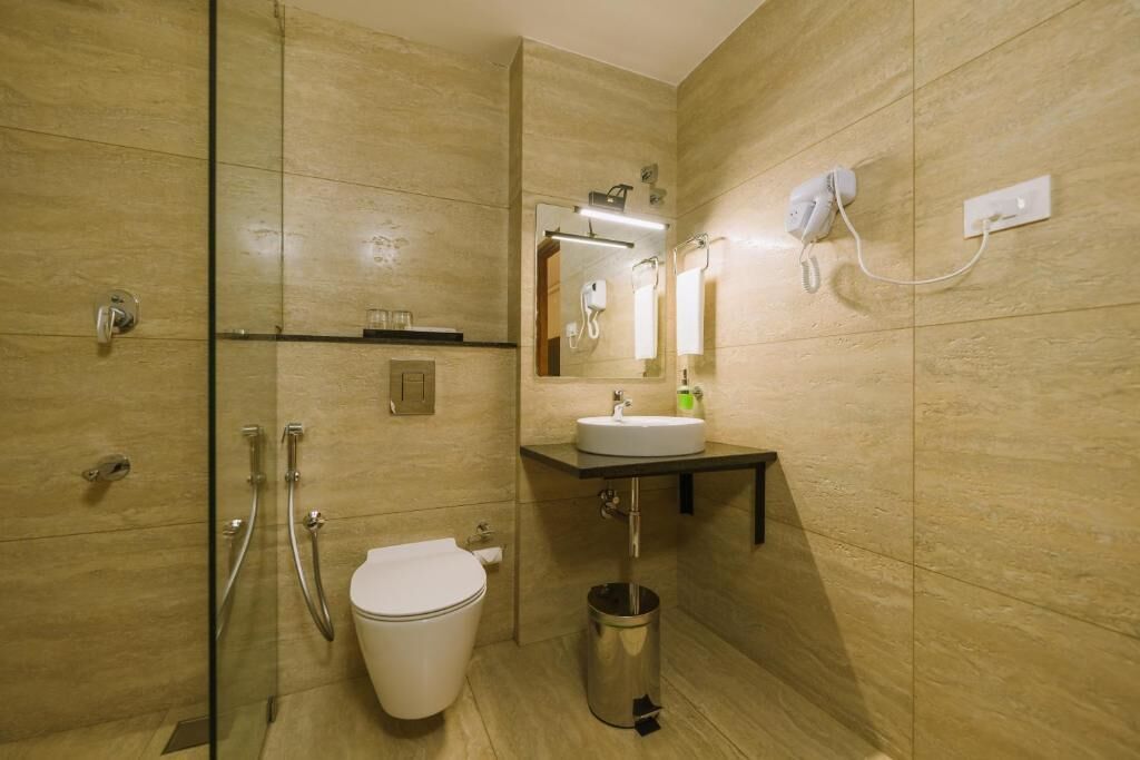 Une salle de bain équipée de toilettes, d’un lavabo, d’un miroir et d’une douche.