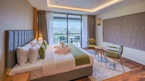 A hotel room with a large bed, a small table, two chairs, and a view of the outdoors.
