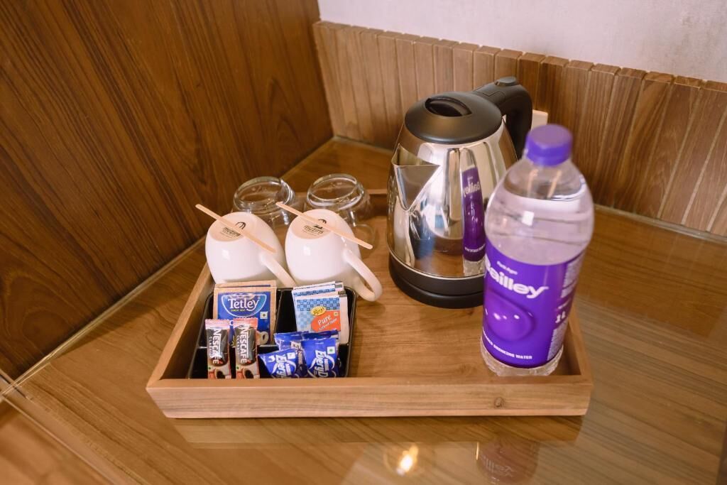 A tray with a kettle, a bottle of water, and various packaged snacks.
