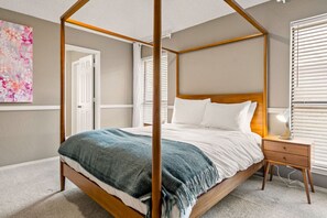 A four-poster bed with a wooden frame, white bedding, and a blue throw blanket. - Nordic-Inspired Getaway | Hot Tub + Fire Pit (North Richland Hills)